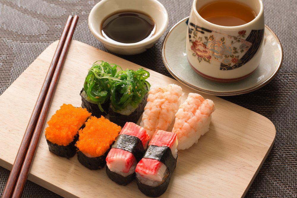 wooden plate with sushi, chop sticks and tea cup