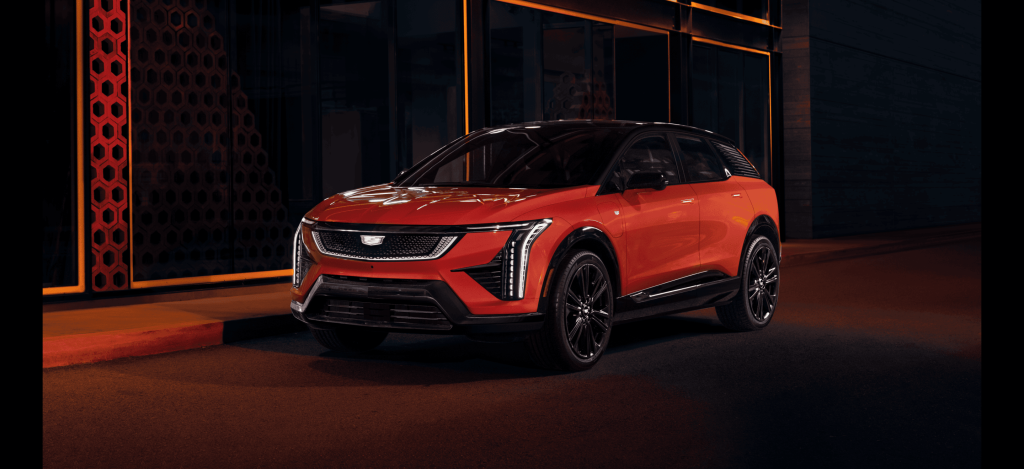 A bright red Cadillac LYRIQ parked on a city street at night.